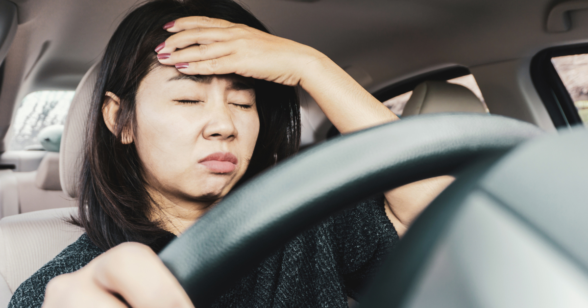 車の運転席で頭を抱えている女性